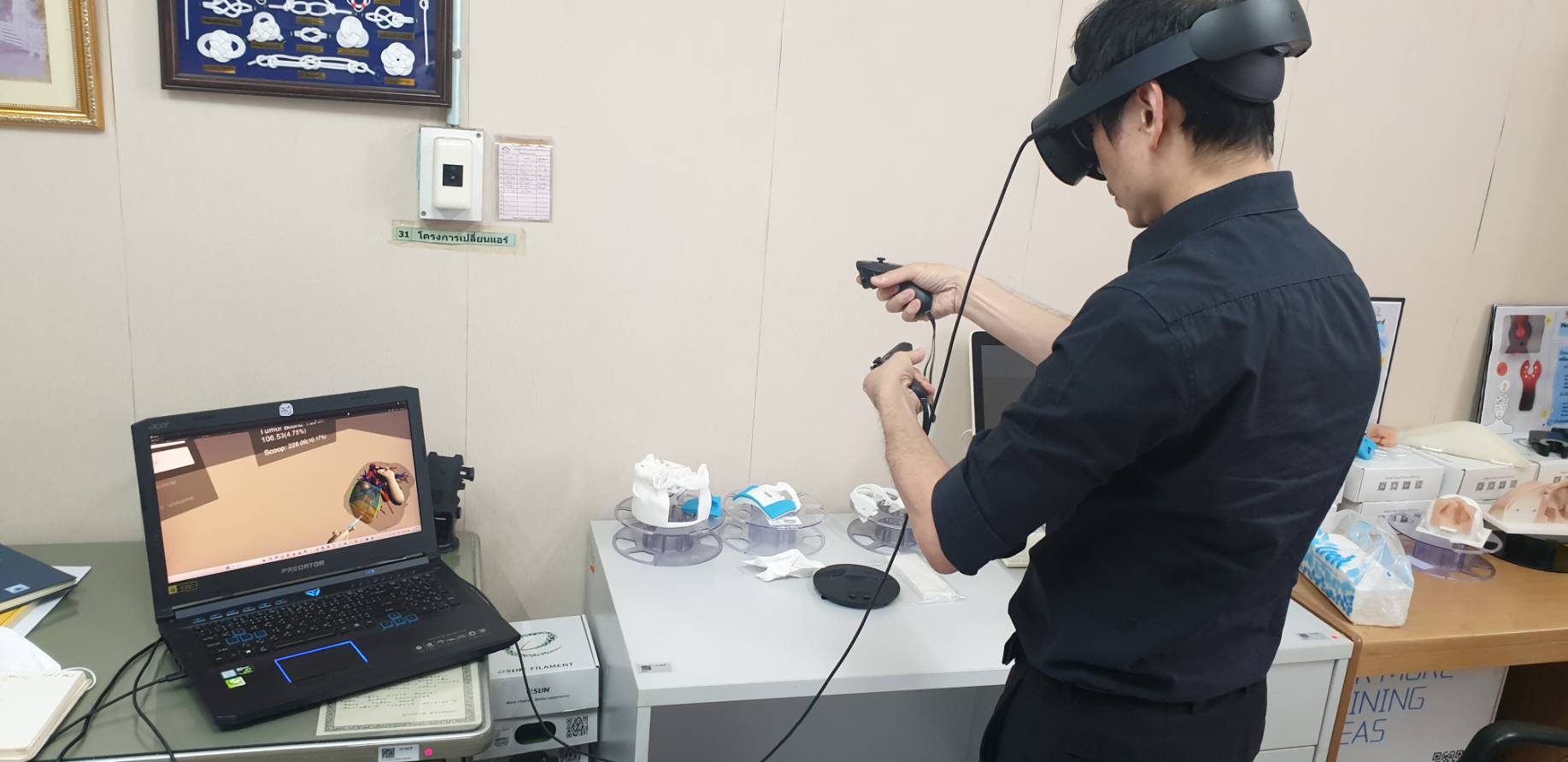 A team member wearing a VR headset while the mirrored view is followed on a laptop